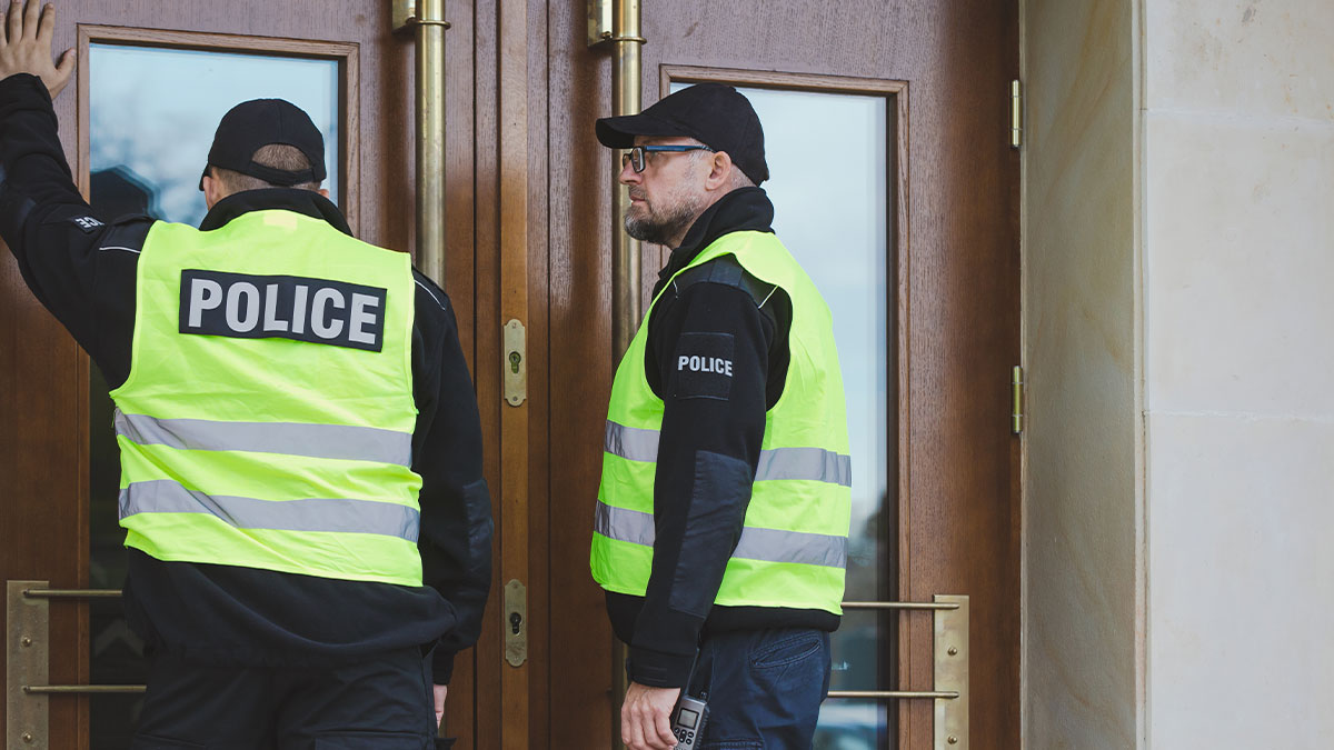 Police officers in yellow vests preparing to break down wooden doors after a worried call about a mentally unstable situation.
