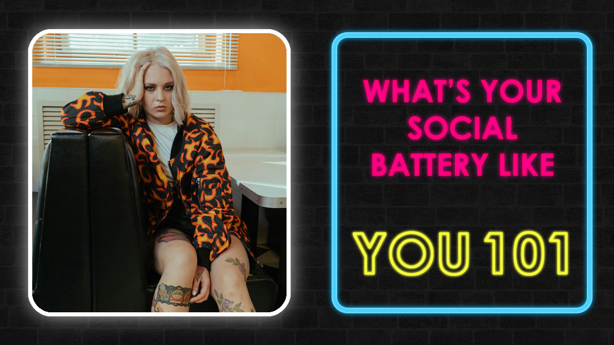 Young woman with tattoos in a patterned jacket sitting beside a neon sign about social battery quiz and self-assessment.