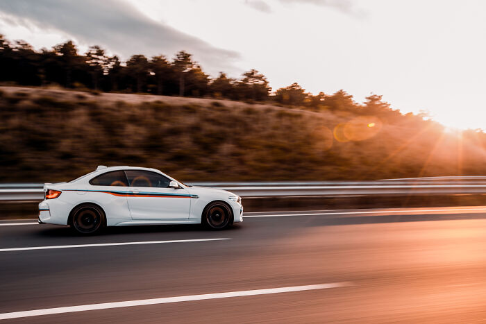 White sports car speeding on highway at sunset, symbolizing stories of people ruining their life with one wrong deed.
