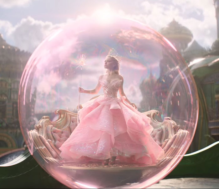 Ariana Grande in an elaborate pink gown inside a glowing bubble, showcasing a ghoulish look with entirely visible ribcage. Ariana Grande in an elaborate pink gown inside a glowing bubble, showcasing a ghoulish look with entirely visible ribcage.