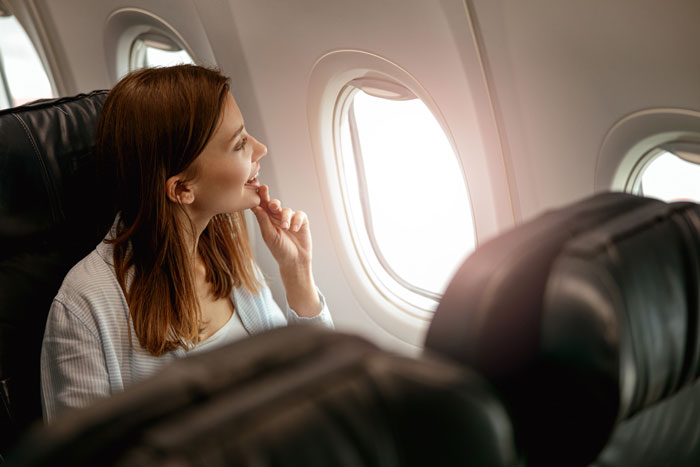Woman on a long flight looking out airplane window while a mom insists she give up her seat during the trip.