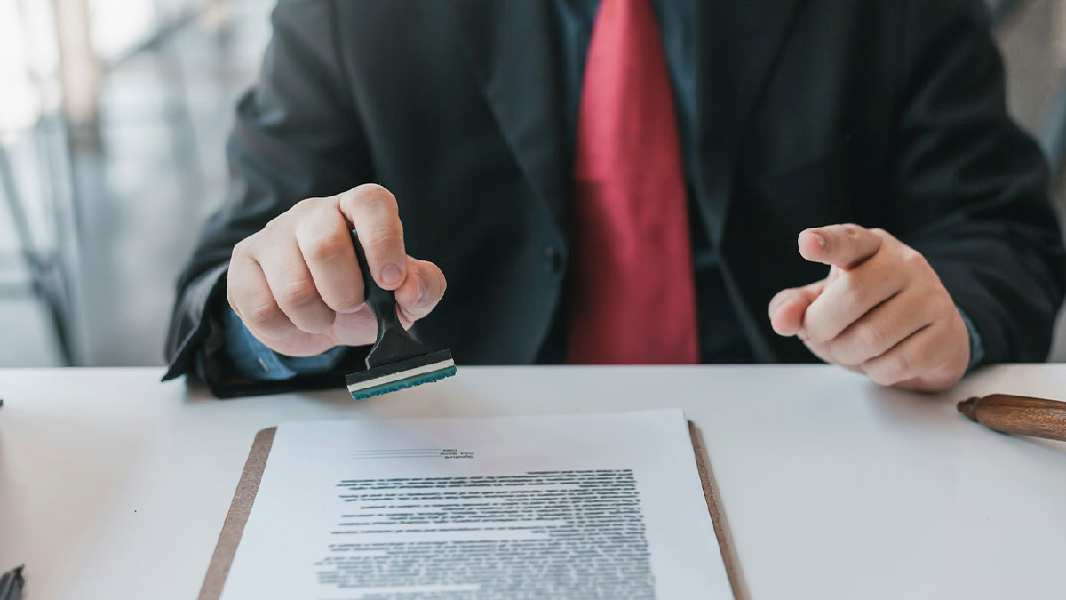 Person in suit stamping a document at desk, symbolizing no peaceful solution to current situation discussions.
