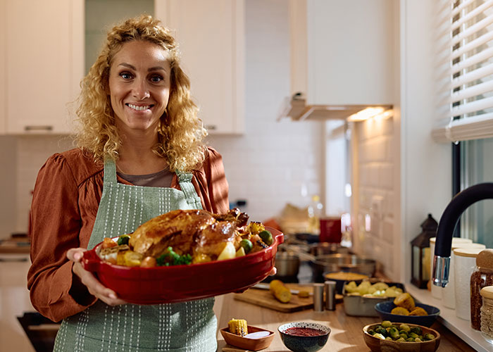 Woman holding a roasted turkey in kitchen, representing tradwife lifestyle and traditional homemaking roles. Woman holding a roasted turkey in kitchen, representing tradwife lifestyle and traditional homemaking roles.