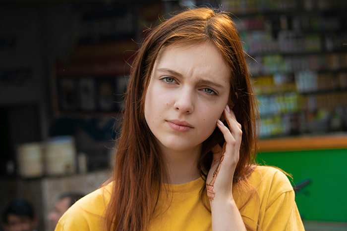 Young woman in a yellow shirt looking thoughtful, representing a woman move Alaska alone decision moment outdoors. Young woman in a yellow shirt looking thoughtful, representing a woman move Alaska alone decision moment outdoors.