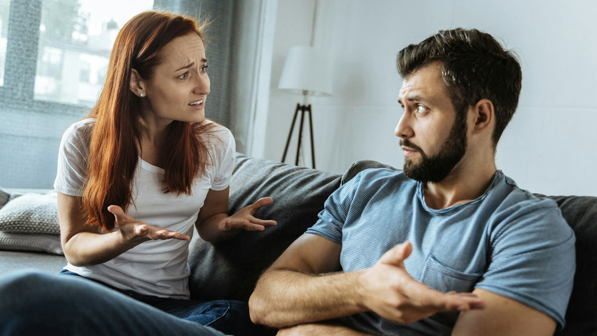 Couple having a tense discussion at home as husband demands wife cancel plans over hair transplant surgery.