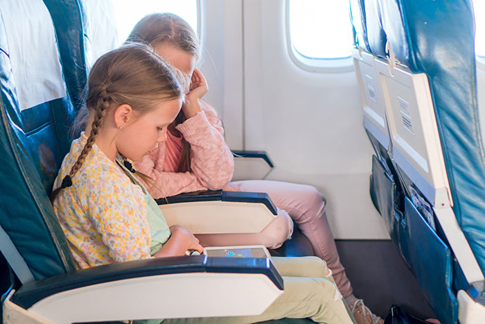 Two children sitting quietly in airplane seats near a window, reflecting a moment about not switching seats on a plane. Two children sitting quietly in airplane seats near a window, reflecting a moment about not switching seats on a plane.