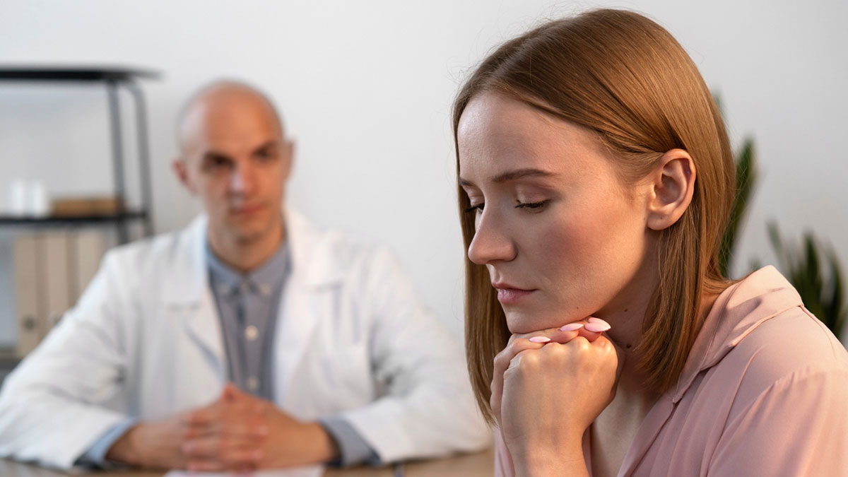 Young woman looking frustrated during a medical consultation, highlighting experiences with dismissive doctors.