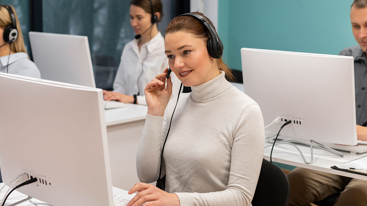 Employee wearing headset working at computer in office, representing employee sabotages work laptop scenario.