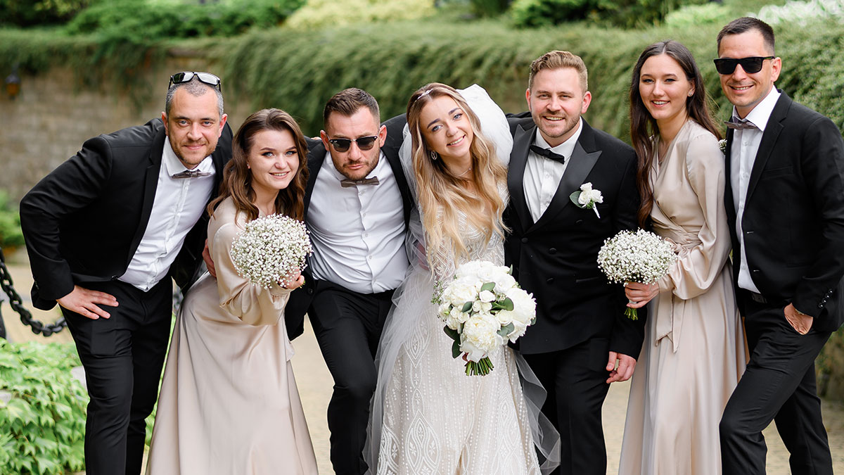 Group of friends at a wedding posing happily outdoors, capturing a moment of joy and celebration.