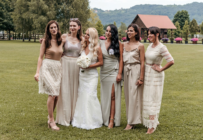 Bride and bridesmaids wearing neutral dresses outdoors, highlighting the contrast with the expectation of wearing color. Bride and bridesmaids wearing neutral dresses outdoors, highlighting the contrast with the expectation of wearing color.
