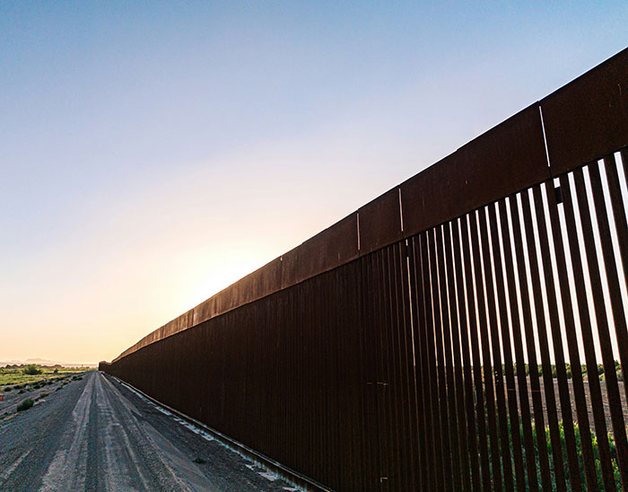 Border fence extending into the distance at sunset, related to cops discovering nearly 400 human bodies in a mysterious building. Border fence extending into the distance at sunset, related to cops discovering nearly 400 human bodies in a mysterious building.