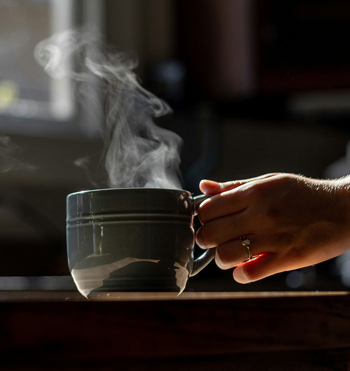 Hand holding a steaming cup of hot beverage symbolizing the landmark domestic violence case involving scalding injuries. Hand holding a steaming cup of hot beverage symbolizing the landmark domestic violence case involving scalding injuries.