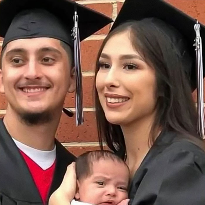 Young couple in graduation gowns holding baby, highlighting tragedy after baby lost his life in car incident.