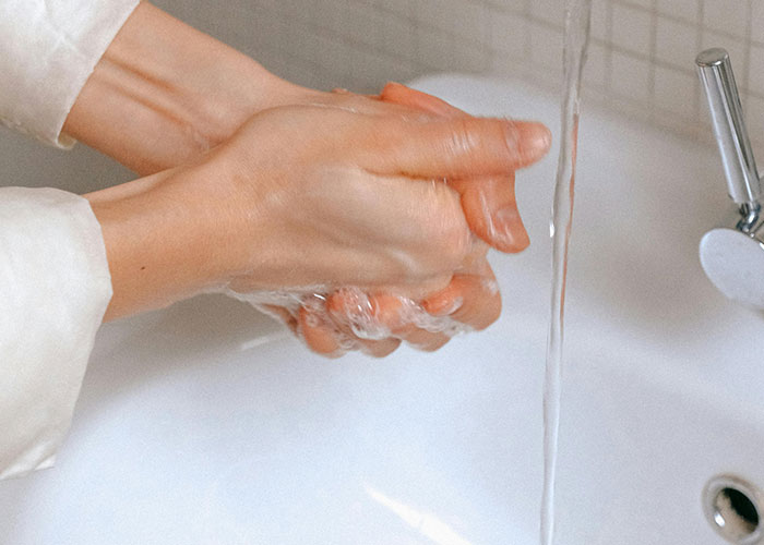 Hands washing under running water in a sink, illustrating bizarre family habits people thought were normal.