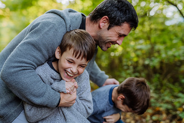 Man happily playing outdoors with children, symbolizing partner caring for children from other men in complex family dynamics Man happily playing outdoors with children, symbolizing partner caring for children from other men in complex family dynamics