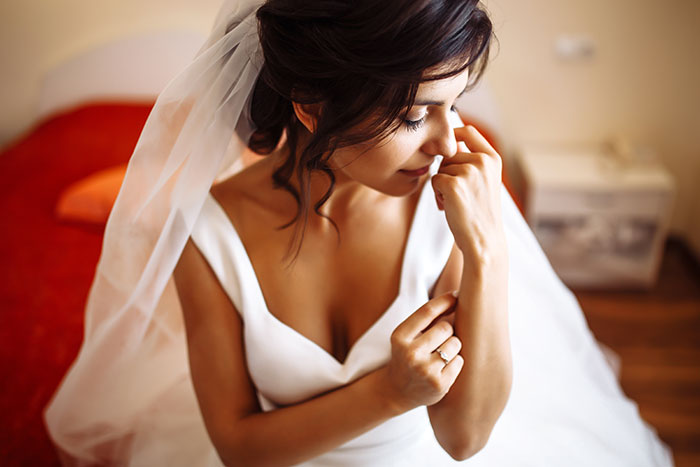 Bride in white dress and veil sitting indoors, reflecting on the occasion with a soft, thoughtful expression. Bride in white dress and veil sitting indoors, reflecting on the occasion with a soft, thoughtful expression.