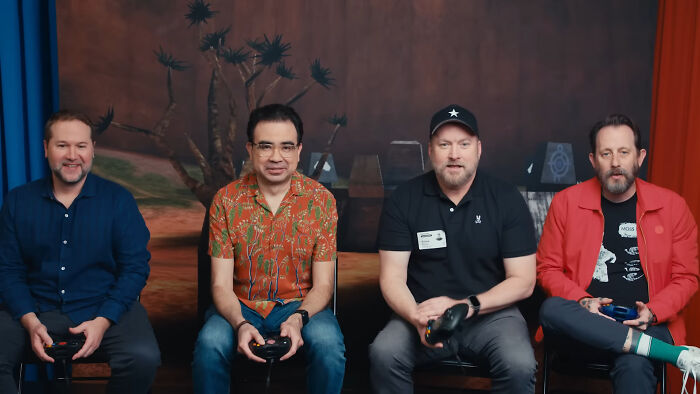 Four men sitting and holding video game controllers, sharing reactions related to unsubscribed YouTubers.