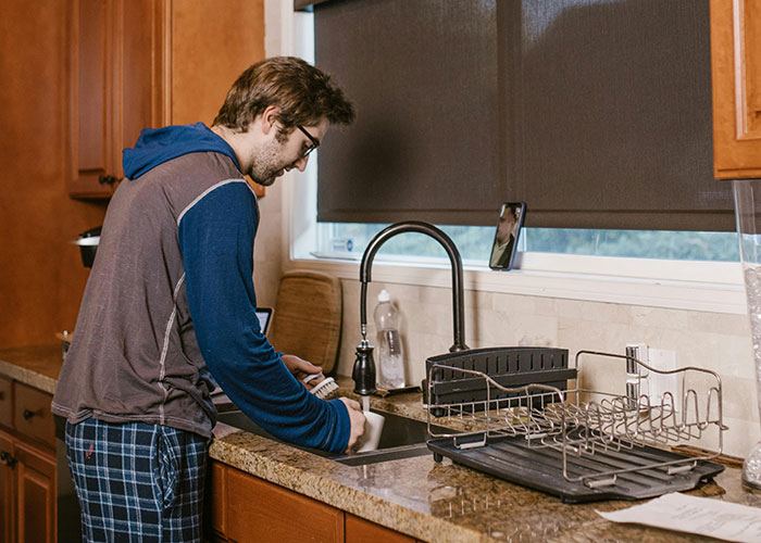 Man washing dishes in kitchen after breakup, reflecting on ex needing to move out and impact on her schooling plans. Man washing dishes in kitchen after breakup, reflecting on ex needing to move out and impact on her schooling plans.