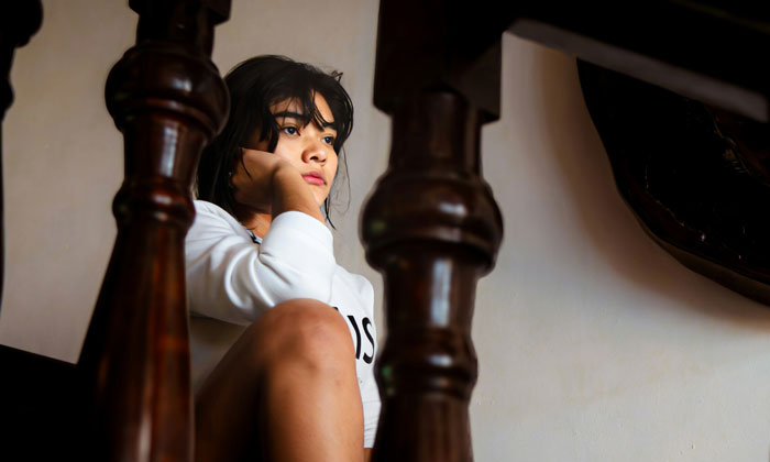 Young girl sitting thoughtfully indoors, reflecting on a makeup moment shared between aunt and niece. Young girl sitting thoughtfully indoors, reflecting on a makeup moment shared between aunt and niece.