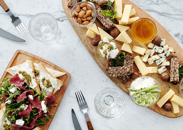 Cheese and nut platter with bread, dips, and salad on wooden boards, illustrating bizarre family food habits.