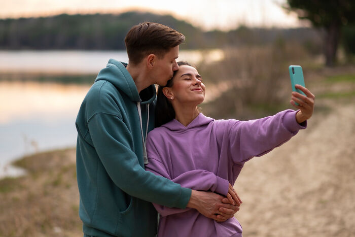 Couple taking a selfie outdoors by the lake, illustrating signs netizens say reveal a couple's days are numbered.