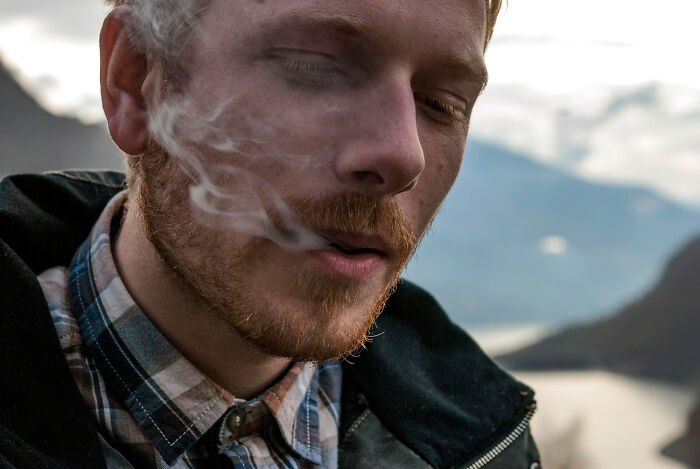 Close-up of a man smoking outdoors, illustrating one of the trends leading to overconsumption affecting lifestyle choices.