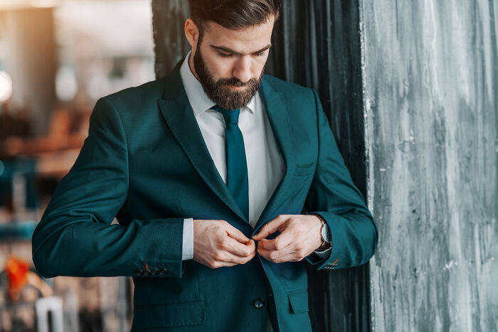 Man in green suit buttoning jacket, symbolizing nostalgia for thank you notes fading from the good old days.