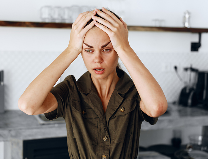 Young woman in kitchen holding head, showing frustration possibly over guy's huge clown collection conflict. Young woman in kitchen holding head, showing frustration possibly over guy's huge clown collection conflict.
