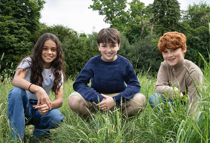 Three young actors sitting in tall grass outdoors, representing Harry Potter fans divided over HBO upcoming show changes. Three young actors sitting in tall grass outdoors, representing Harry Potter fans divided over HBO upcoming show changes.