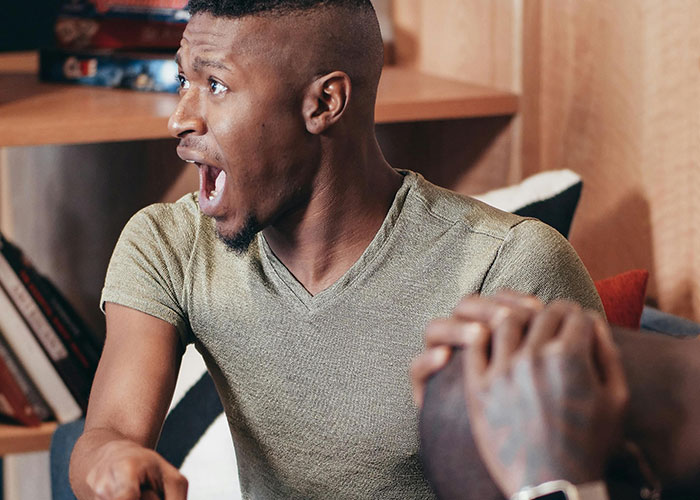 Man reacting with surprise while sharing bizarre family stories in a casual living room setting