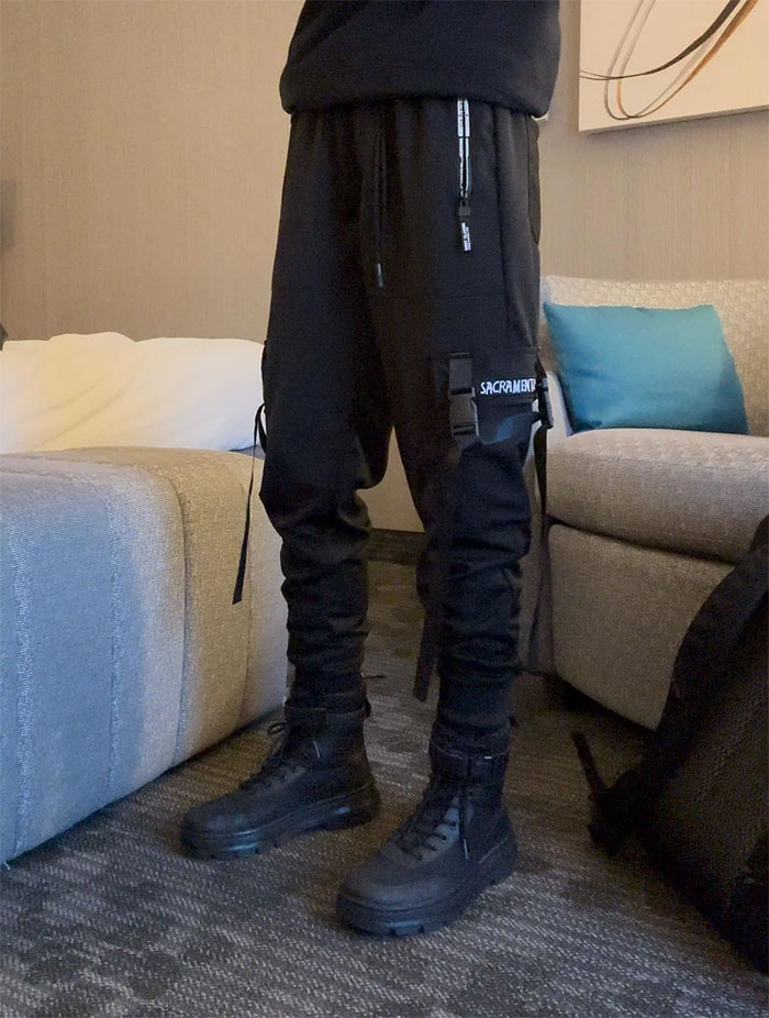 Young person standing in black pants and boots indoors, illustrating a boomer complaint about stranger’s pants and response. Young person standing in black pants and boots indoors, illustrating a boomer complaint about stranger’s pants and response.