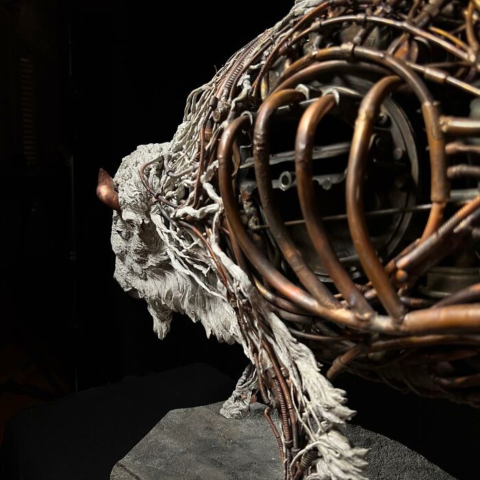 Buffalo sculpture crafted from scrap metal and wire showcasing intricate animal sculpture artistry on a stone base.
