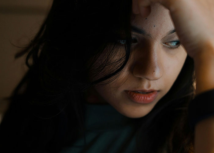 Worried woman rethinks her relationship after a red-flag argument, showing fear and emotional distress in dim lighting. Worried woman rethinks her relationship after a red-flag argument, showing fear and emotional distress in dim lighting.