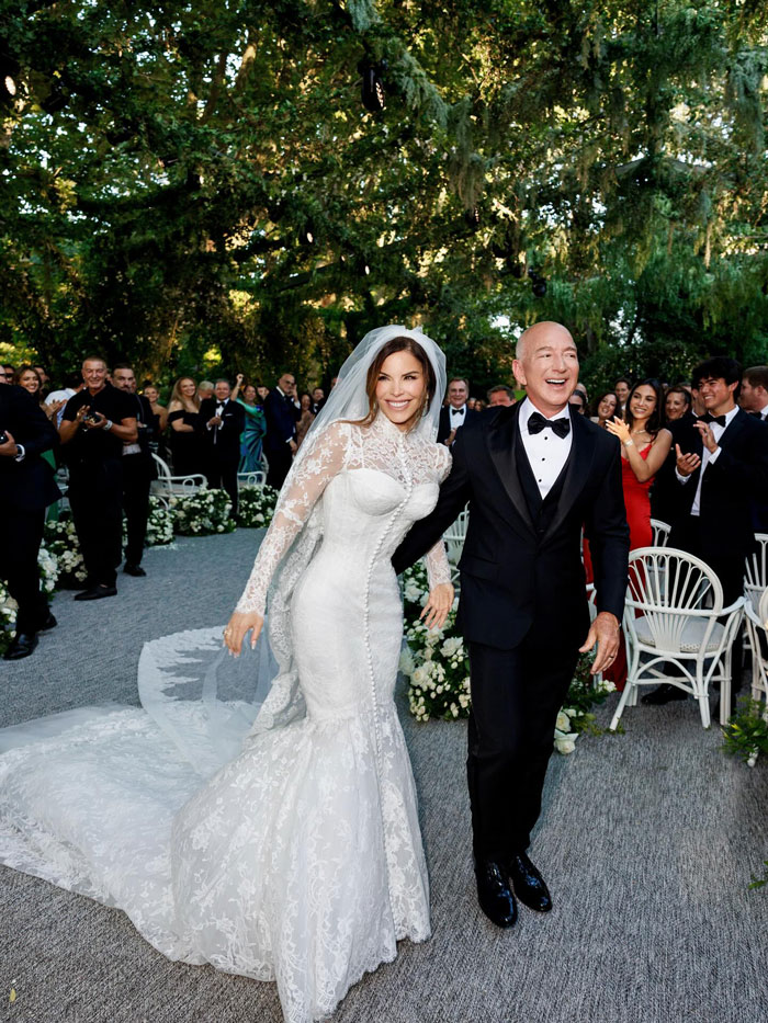 Jeff Bezos in a tuxedo with full hair, walking with bride Lauren Sánchez at their outdoor wedding ceremony. Jeff Bezos in a tuxedo with full hair, walking with bride Lauren Sánchez at their outdoor wedding ceremony.