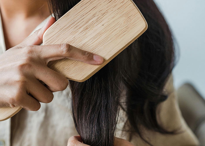 Person brushing long dark hair with a wooden brush, illustrating bizarre family habits some thought were normal.