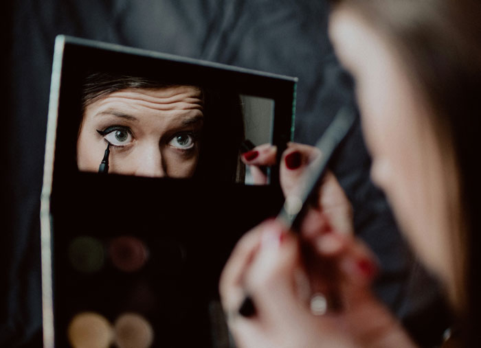 Woman applying makeup using a compact mirror, focusing on eyeliner, with niece’s makeup treated like Sephora products. Woman applying makeup using a compact mirror, focusing on eyeliner, with niece’s makeup treated like Sephora products.