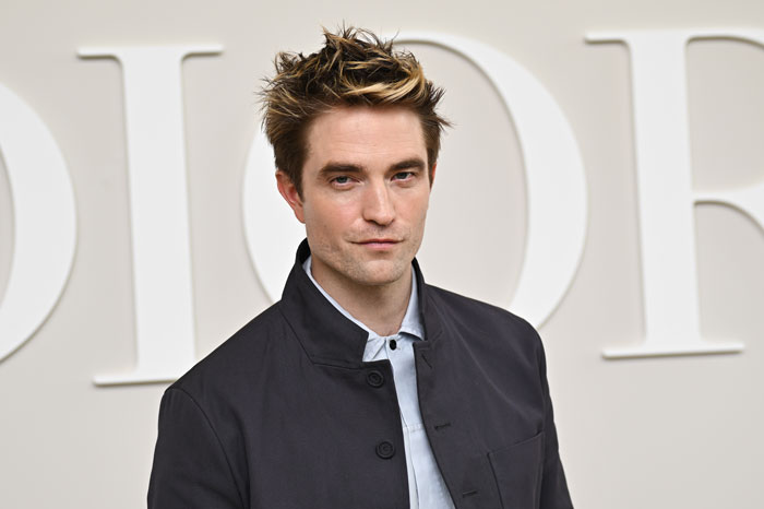 Robert Pattinson posing at an event, dressed in a black jacket, related to Twilight intimate scene discussion. Robert Pattinson posing at an event, dressed in a black jacket, related to Twilight intimate scene discussion.