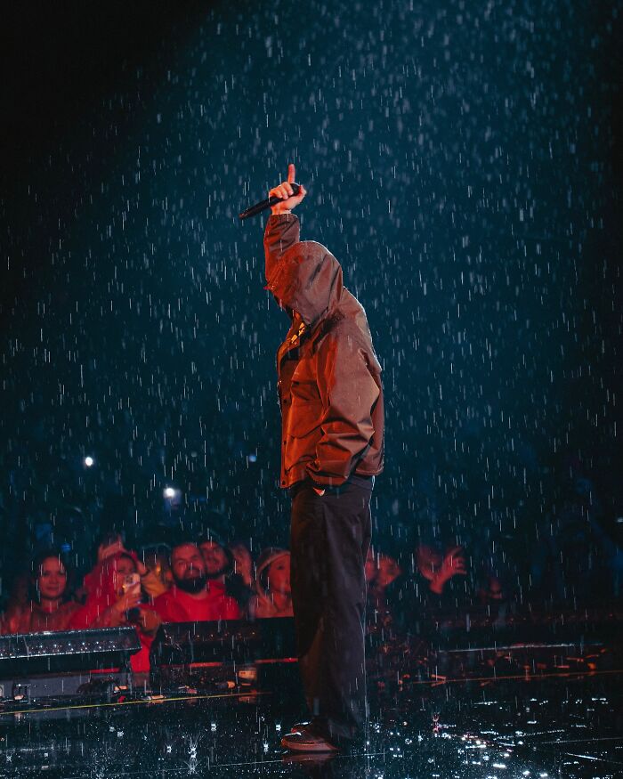 Performer on stage in rain during Justin Timberlake Romania show with audience in the background capturing the moment on phones Performer on stage in rain during Justin Timberlake Romania show with audience in the background capturing the moment on phones