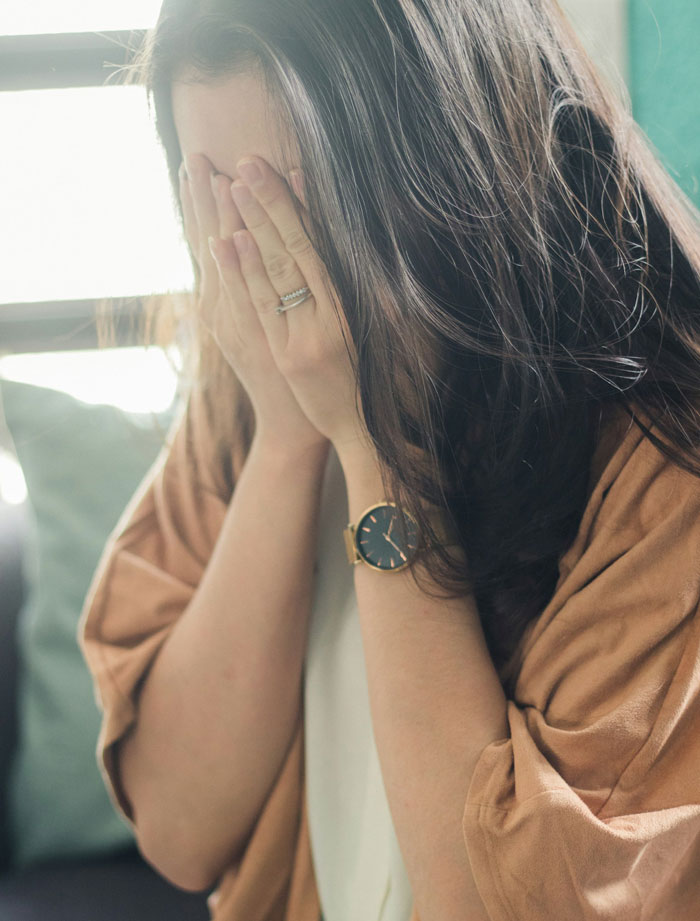 Woman covering her face with hands, expressing stress or regret related to menstruation celebration going too far. Woman covering her face with hands, expressing stress or regret related to menstruation celebration going too far.