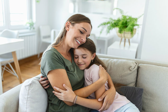 Mother and 12-year-old daughter sharing a warm hug during a menstruation celebration at home. Mother and 12-year-old daughter sharing a warm hug during a menstruation celebration at home.