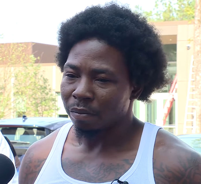 Man with afro hairstyle wearing a white tank top speaking outside, related to 3-year-old boy in temporary foster care incident. Man with afro hairstyle wearing a white tank top speaking outside, related to 3-year-old boy in temporary foster care incident.