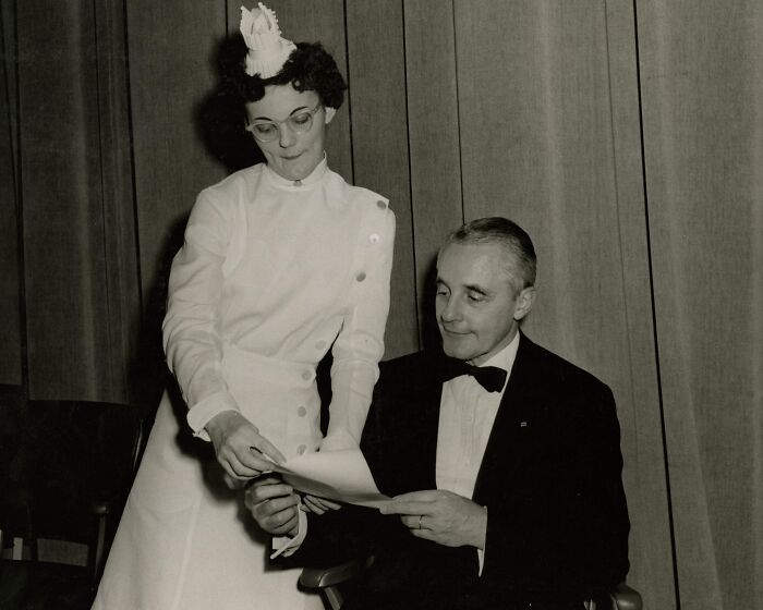 Vintage photo of a nurse in traditional uniform assisting a man in a suit, showcasing healing and hope in nursing history.