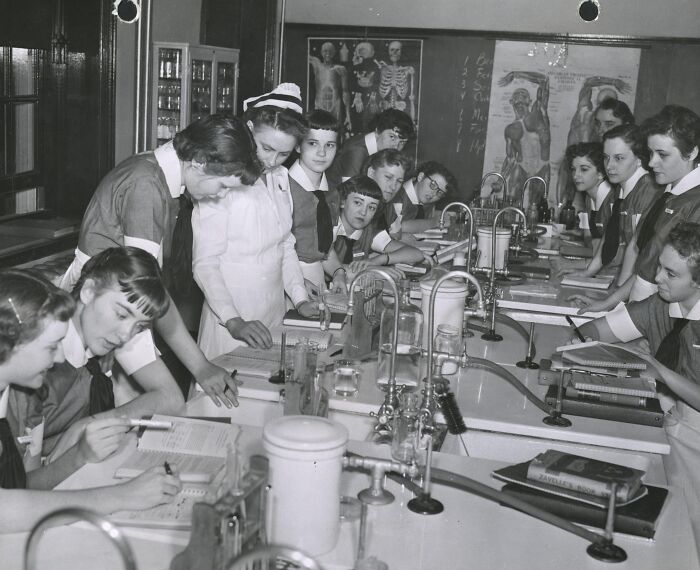 Vintage photo of nurses in training, studying medical texts and equipment, embodying healing and hope in healthcare history.
