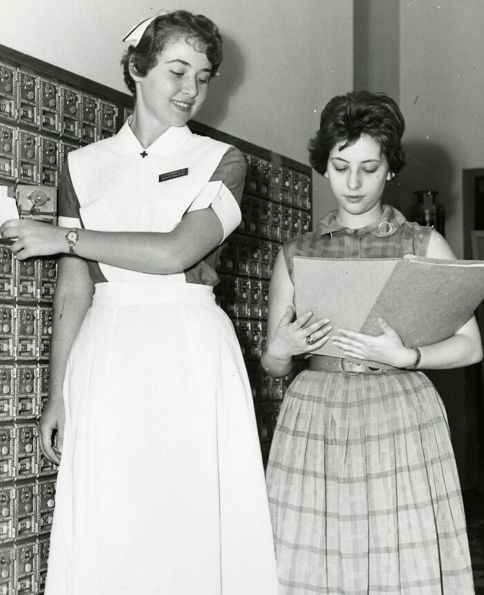Vintage nurses in classic uniforms sorting mail and reviewing documents in a hospital setting, showcasing healing and care.