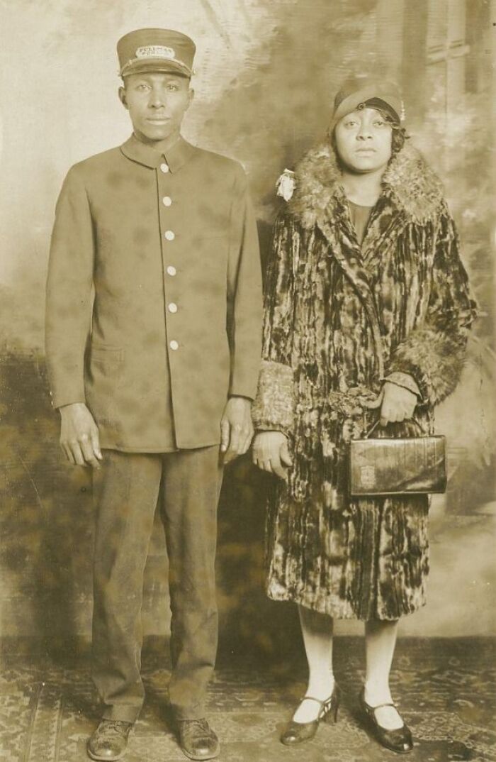 Vintage postcard from the 1930s featuring a man in uniform and a woman in a fur coat and cloche hat posing indoors.