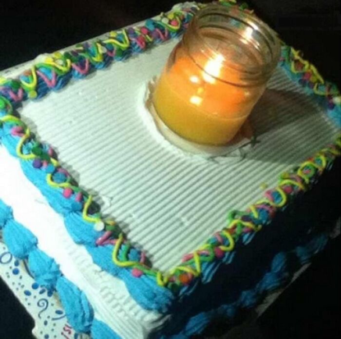 Square cake with colorful icing and a candle jar placed in the center, showing a suspiciously unbothered attitude.