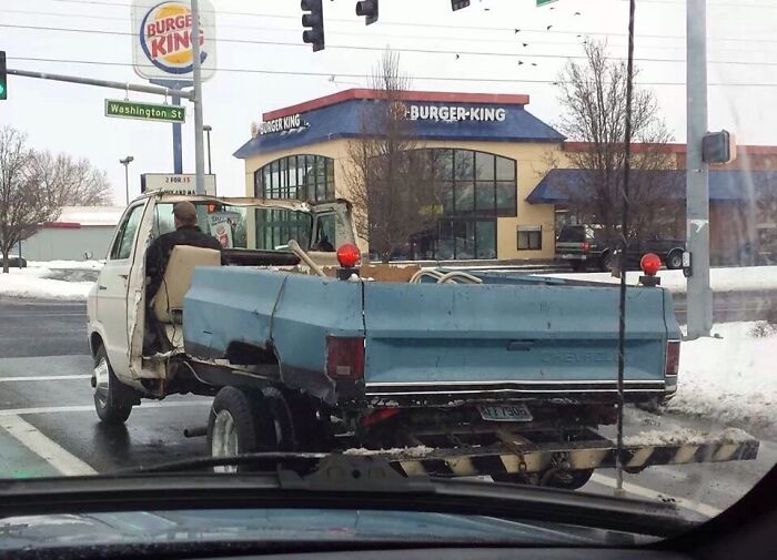 Man driving a truck with a detached truck bed on a snowy street, showing suspiciously unbothered attitude.