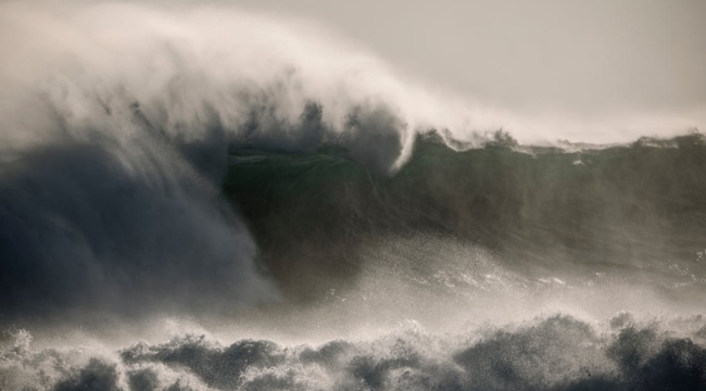 Large ocean wave forming, illustrating the natural cause of a tsunami often caused by underwater seismic activity.