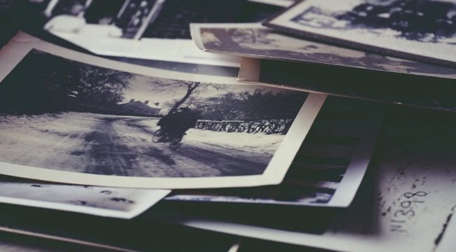 Stack of old black and white photographs representing memory linked to the sense most closely tied to memory in science.