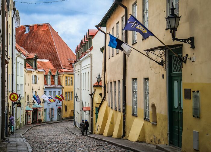 Historic European street in one of the smartest countries shaping the future with traditional architecture and national flags displayed.